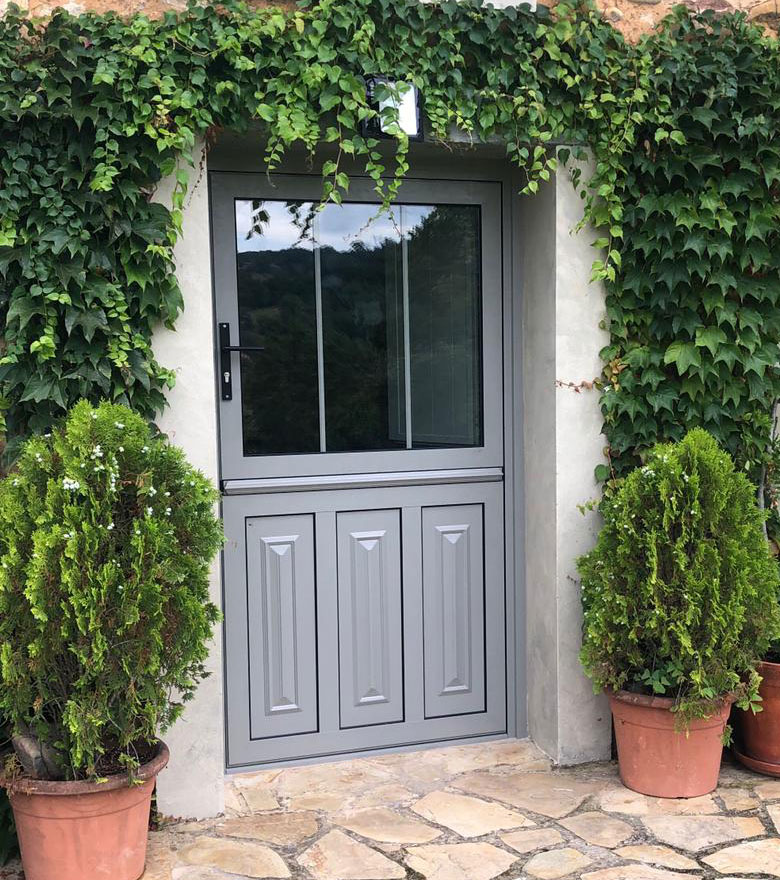 Aluminios Tecnoal - puerta en dos secciones, con ventana incluida de acceso a vivienda particular en aluminio color gris y estilo rústico